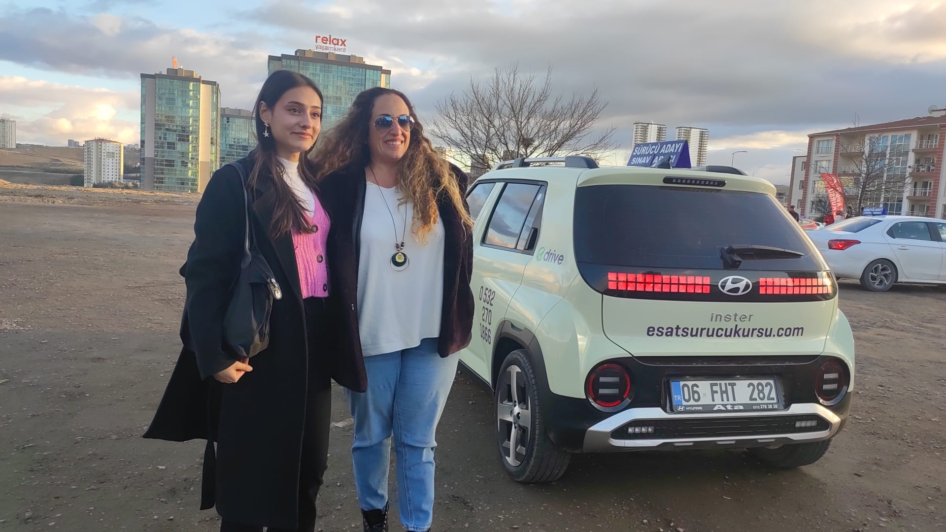Esat Sürücü Kursu elektrikli eğitim otomobilinin yanında iki kişi