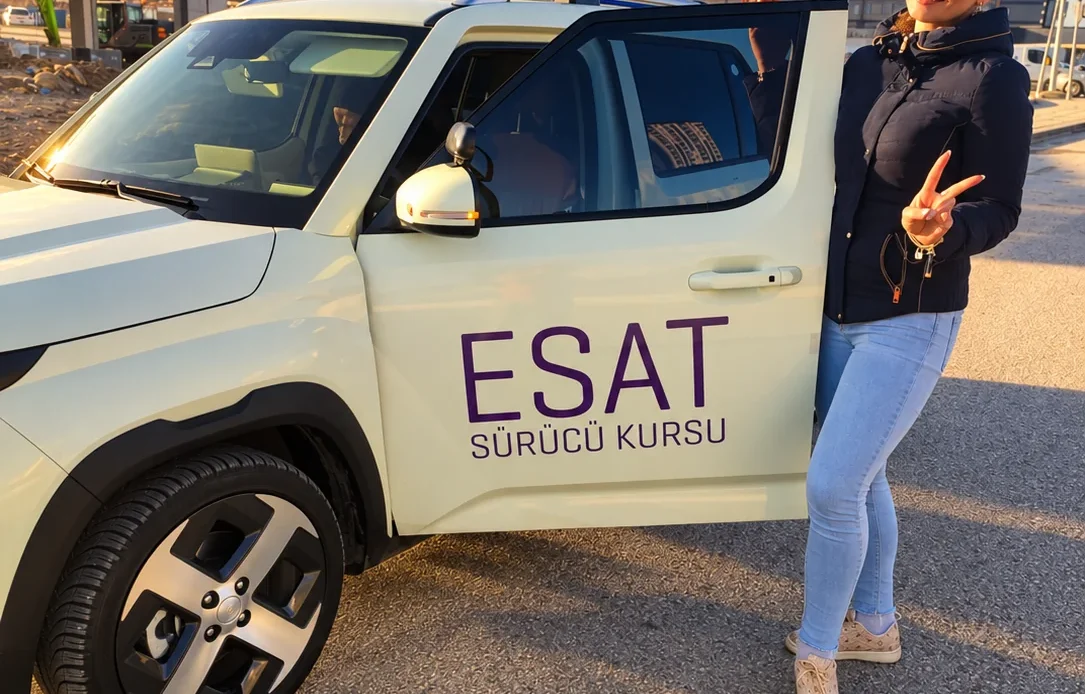 Çankaya’da navigasyonla ilk sürüş için Esat Sürücü Kursu eğitim aracının yanında duran yetişkin.